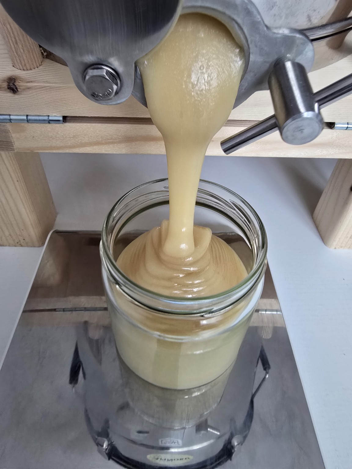 Cremiger Honig wird in der Hobbyimkerei frisch in ein Glas abgefüllt
